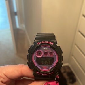 Black women’s G-Shock watch with hot pink and purple face and hot pink buttons